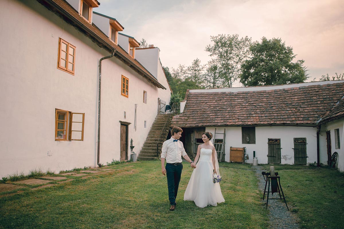 Bride and groom walking in the farmhouse courtyard