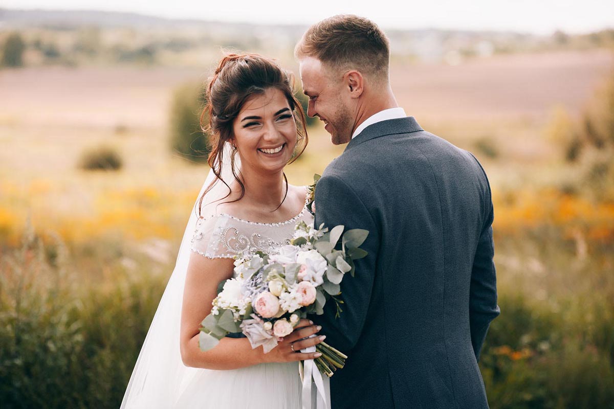 Happy bride and groom in the grass fields