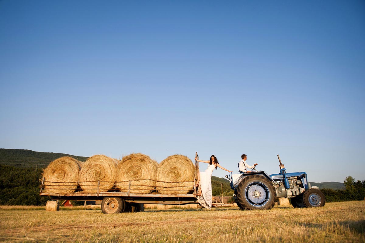 Playful bride and groom taking a ride on a tractor